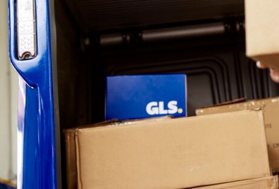 GLS-paketteja ja GLS-työntekijä on iloisena taustalla.